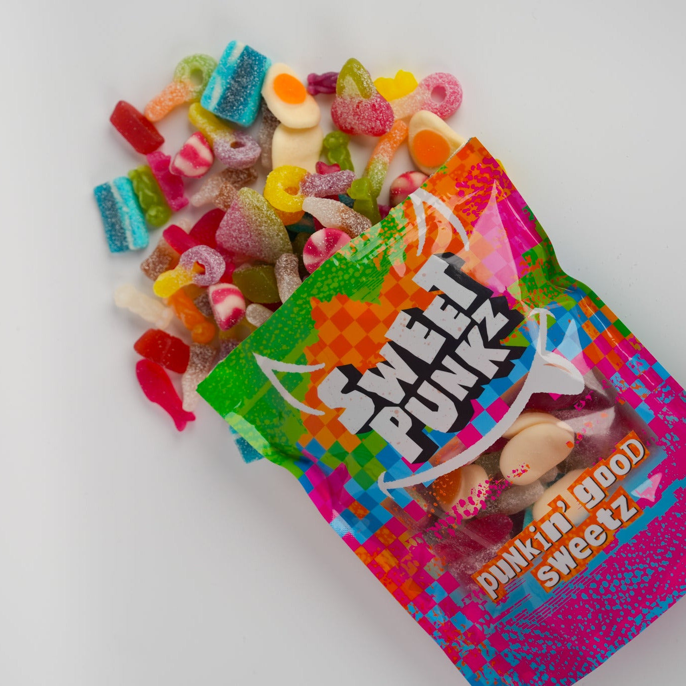 Colorful Sweet Punk candy bag with gummy candies spilling out on a white background
